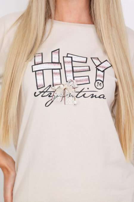 A bézs színű, divatos DORINA női tavaszi pamut felső masnival és applikációval díszített modell, mely egyszerre ötvözi magában a játékosságot és a nőiességet.