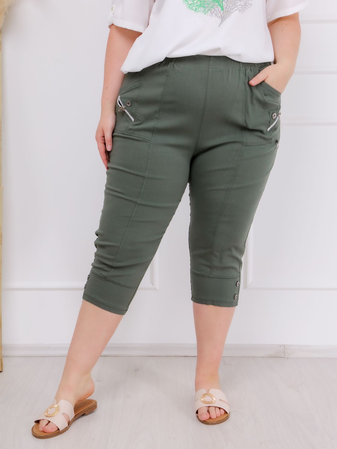 Az elegáns, zöld színű ANA elegáns PLUS SIZE női caprinadrág magas derékkal és praktikus zsebekkel, amely minden alkatnak nőies és magabiztos megjelenést nyújt!