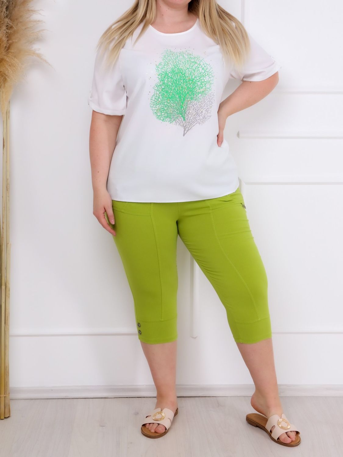 A klasszikus, lime zöld színű ANA elegáns PLUS SIZE női caprinadrág elegáns vonalvezetéssel, amely minden alkatot előnyösen formál és kiemeli a női idomokat.